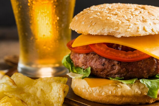 Bicchiere di birra con cheeseburger e patatine