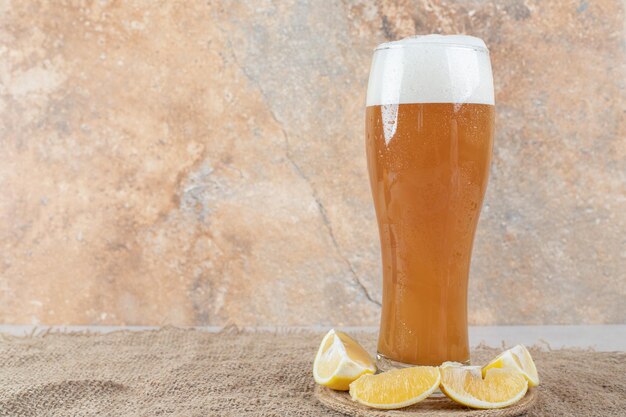 Bicchiere di birra con fette di limone su tela.