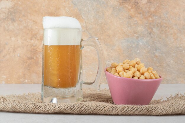 Bicchiere di birra con una ciotola di piselli su tela
