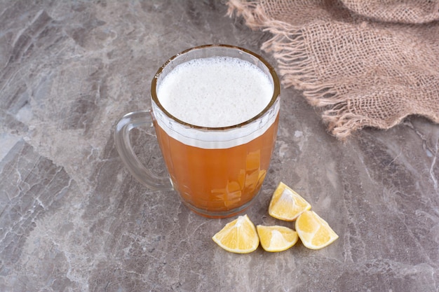 Bicchiere di birra e fette di limone sulla superficie in marmo