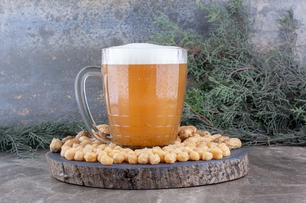 Bicchiere di birra, piselli e arachidi sul pezzo di legno