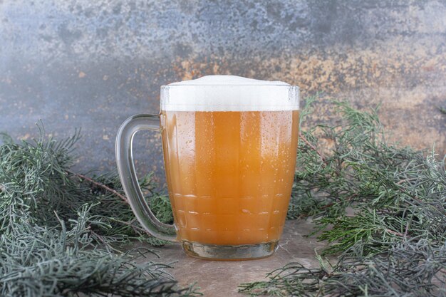 Bicchiere di birra sul tavolo di marmo con ramo di pino. Foto di alta qualità