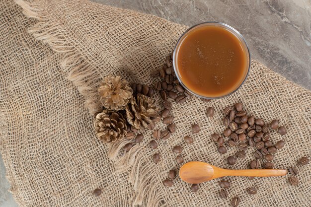 Bicchiere di caffè con chicchi di caffè e cucchiaio su tela