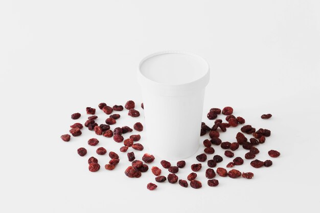 Bicchiere di cartone bianco tra frutta secca