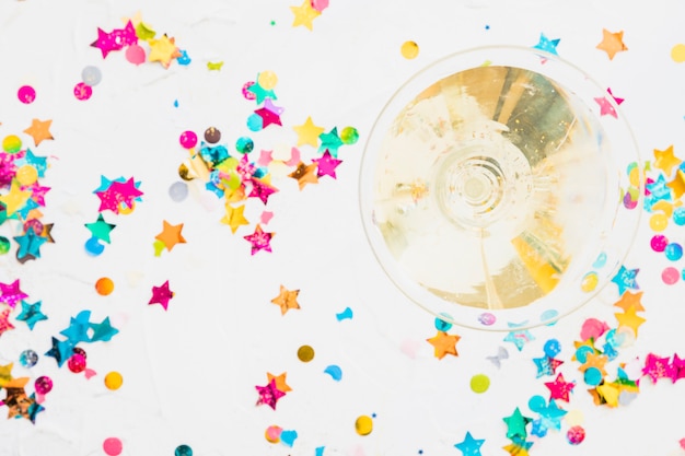Bicchiere di champagne con lustrini stella sul tavolo bianco