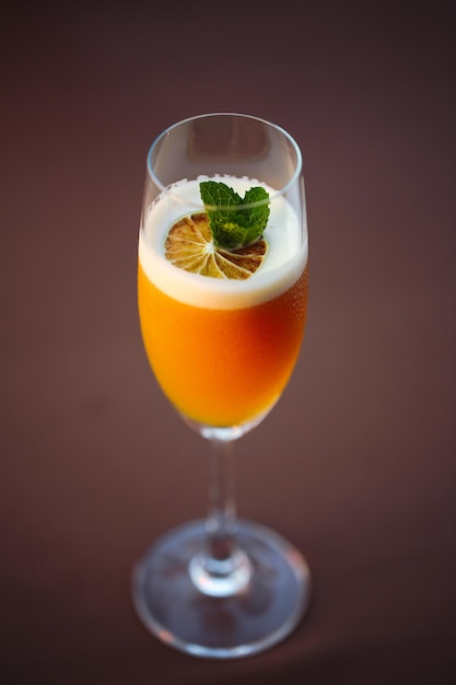 Bicchiere di cocktail arancione decorato con contorno arancione sullo sfondo del bancone del bar