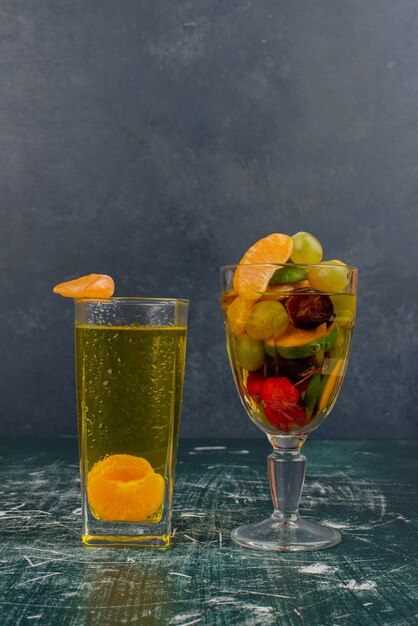Bicchiere di frutta mista e succo di mandarino sul tavolo di marmo