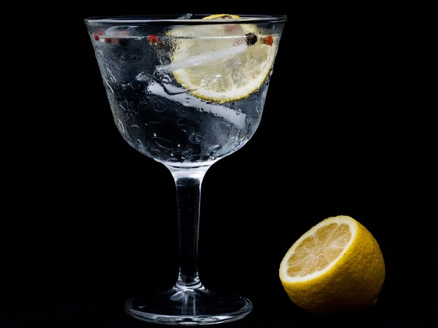 Bicchiere di Gintonic con limone e ghiaccio isolato su una parete nera