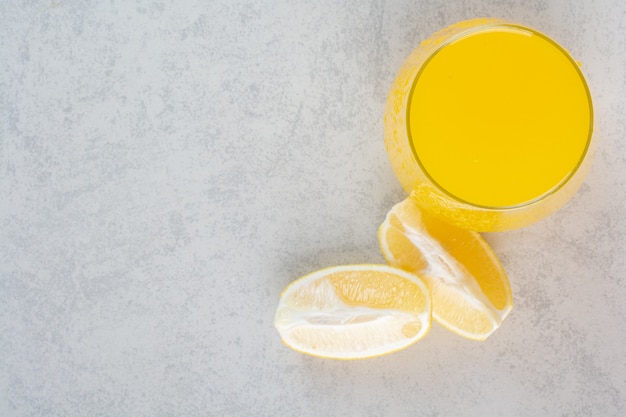 Bicchiere di limonata fresca con fette di limone su grigio.