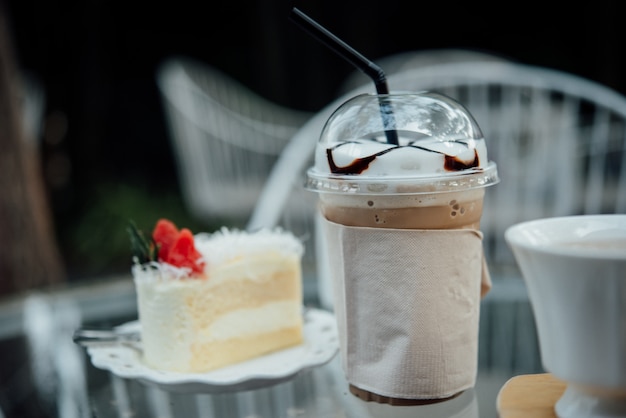 bicchiere di plastica di caffè ghiacciato con torta sul tavolo nella caffetteria