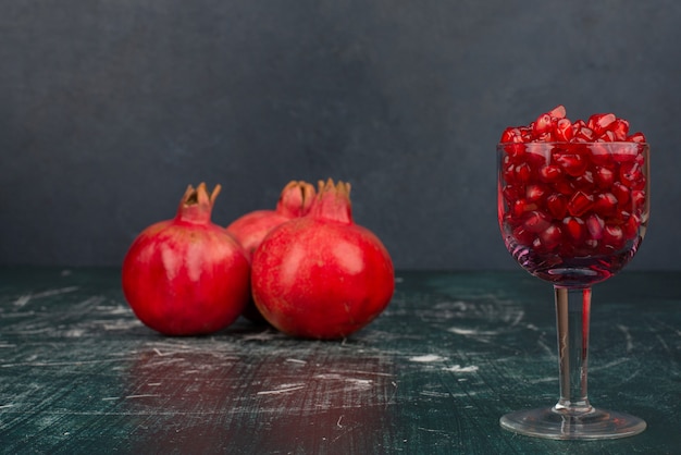 Bicchiere di semi di melograno e melograno sulla superficie in marmo.