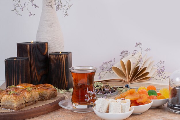 Bicchiere di tè, dolci e tradizionali vari baklavas sul tavolo di marmo.