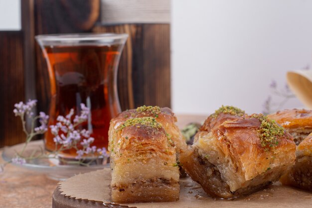 Bicchiere di tè e baklava tradizionale al pistacchio sul tavolo di marmo.