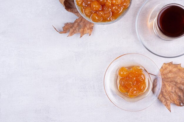 Bicchiere di tè e marmellata di frutti di bosco su bianco.