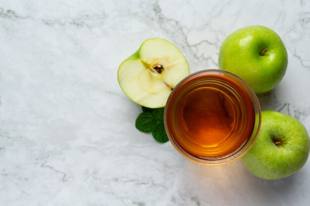 Bicchiere di tè sano alla mela verde messo accanto a mele verdi fresche