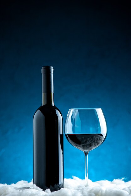 Bicchiere e bottiglia di vino vista frontale su sfondo blu
