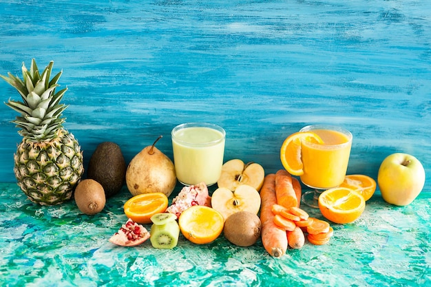Bicchieri con succhi organici e crudi di frutta e verdura su fondo di legno
