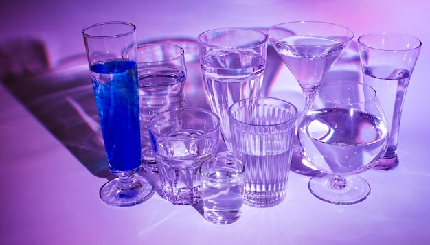 Bicchieri d&#39;acqua con cocktail blu su sfondo colorato