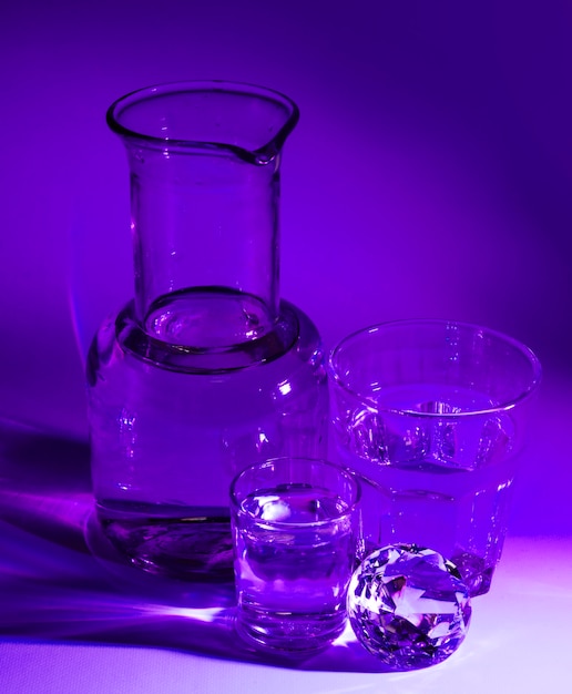 Bicchieri d&#39;acqua trasparenti; diamante e becher sullo sfondo viola