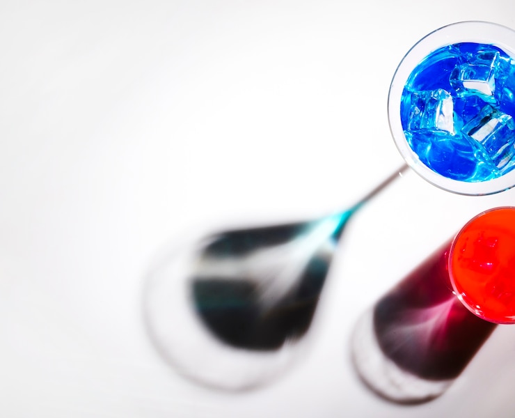 Foto gratuito bicchieri da cocktail blu e rossi con ombra splendente su sfondo bianco