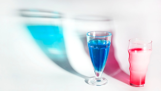 Bicchieri da cocktail rossi e blu con ombra su sfondo bianco