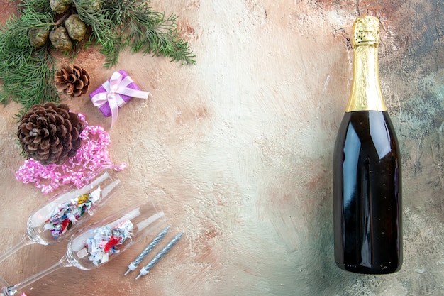 Bicchieri da vino vista dall'alto con piccoli regali e bottiglia di champagne su sfondo chiaro