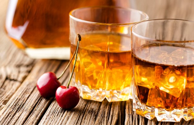 Bicchieri da whisky in primo piano con ghiaccio e ciliegie