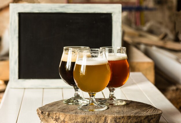 Bicchieri di diversi tipi di birra su fondo in legno