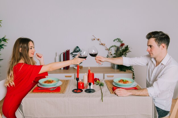 Bicchieri di vino tintinnanti delle coppie felici durante la cena romantica