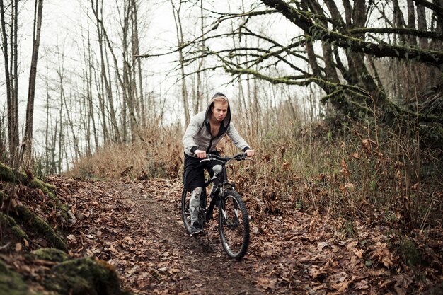 Bicicletta attiva di guida del giovane nella foresta