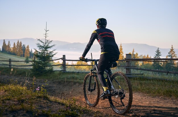 Bicicletta di guida del giovane sorridente sulla strada di montagna