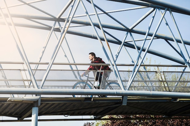 Bicicletta di guida dell&#39;uomo di vista laterale sul ponte