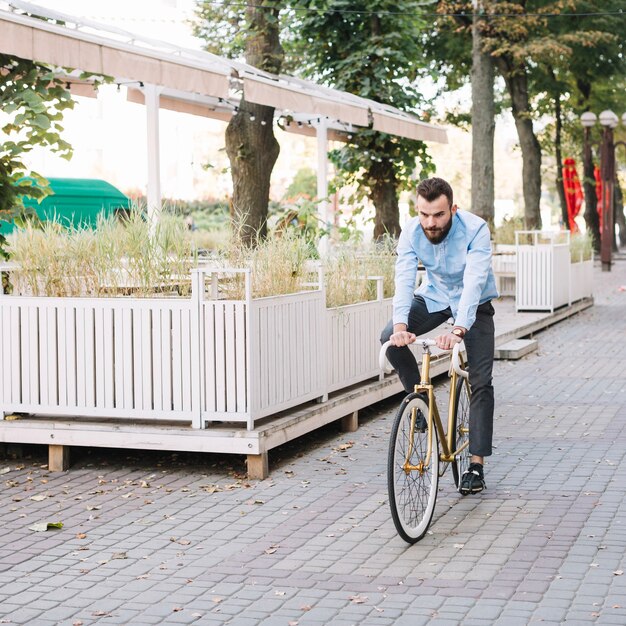 Bicicletta di guida dell&#39;uomo vicino al caffè all&#39;aperto