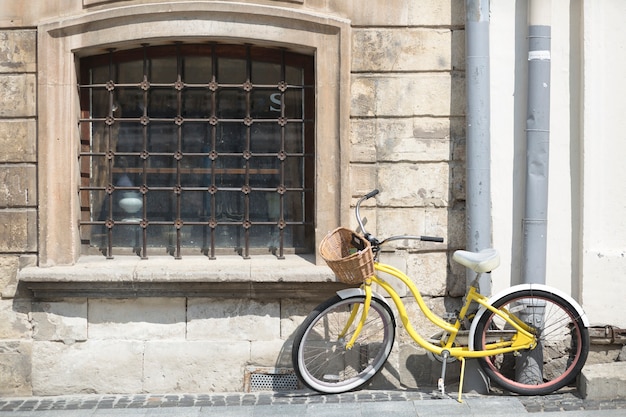 Bicicletta gialla con cesto di fronte al vecchio muro