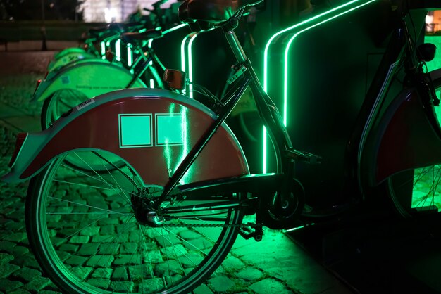 Biciclette parcheggiate per la condivisione con la notte di illuminazione verde a Bucarest, Romania