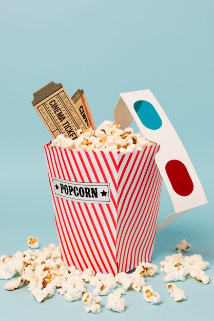 Biglietti del cinema e occhiali 3d sul contenitore di popcorn su sfondo blu