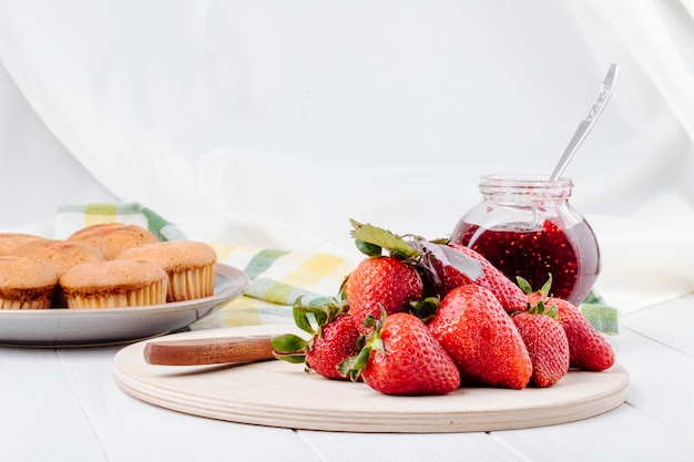 Bigné e marmellata di fragole freschi della fragola di vista laterale su fondo bianco