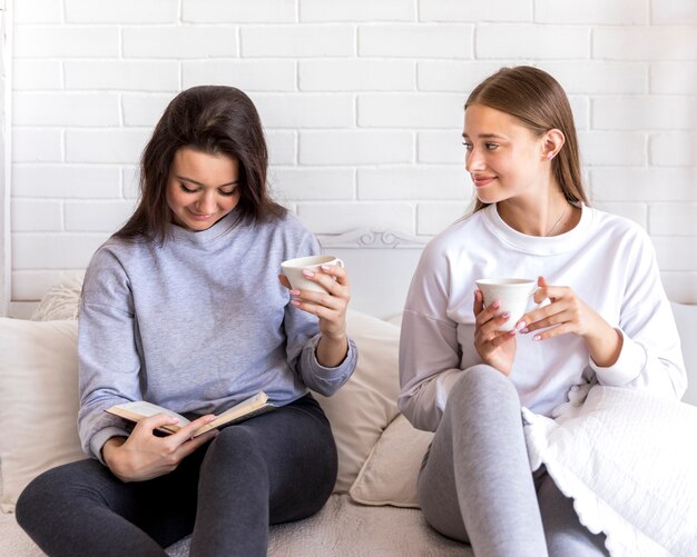 Bionda carina guardando la sua ragazza durante la lettura