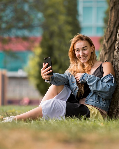 Bionda che cattura un selfie accanto a un albero