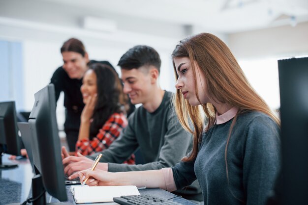 Bionda concentrata. Gruppo di giovani in abiti casual che lavorano nell'ufficio moderno