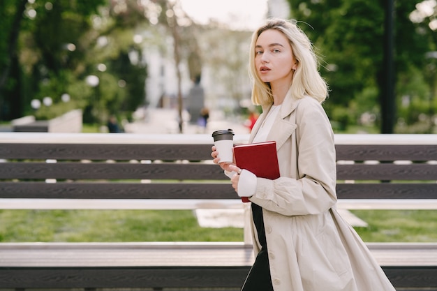 Bionda in una città estiva con una tazza di caffè