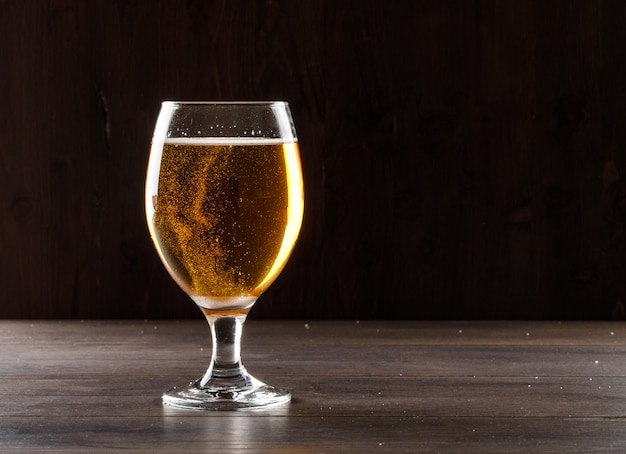 Birra in una vista laterale di vetro di calice su una tavola di legno