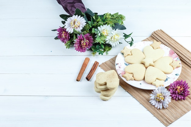 Biscotti a forma di cuore e stella di vista di alto angolo, fiori in tovaglietta con cannella