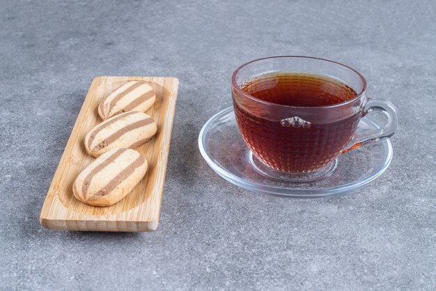 Biscotti a forma ovale su piatto di legno con tazza di tè