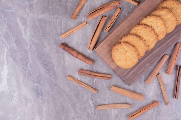 Biscotti al burro con bastoncini di cannella su un piatto di legno