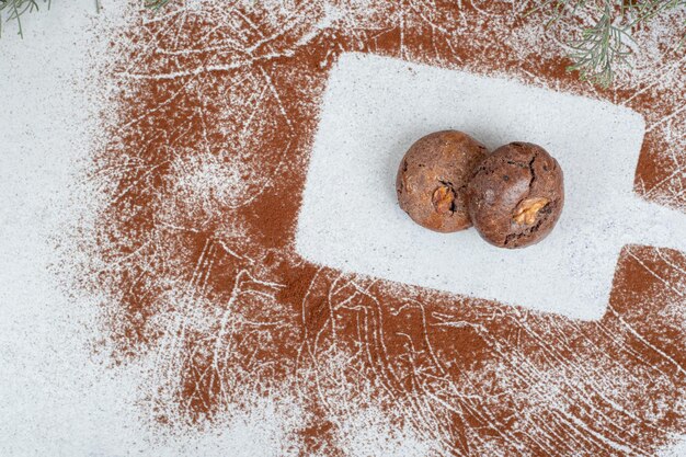Biscotti al cioccolato con cacao in polvere su superficie bianca.