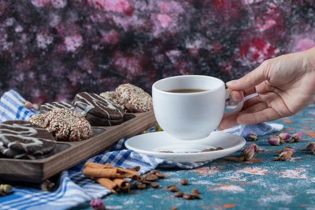 Biscotti al cioccolato e sesamo in un piatto di legno con una tazza di tè.