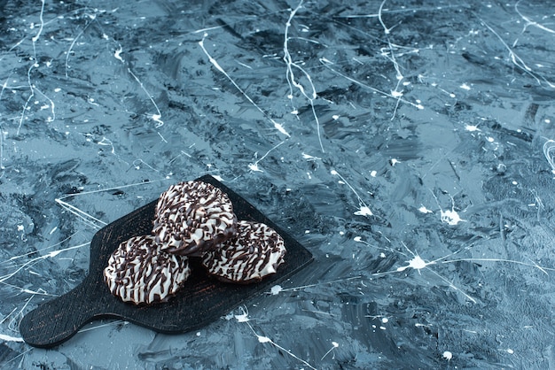 Biscotti al cioccolato su un tagliere, sul tavolo blu.