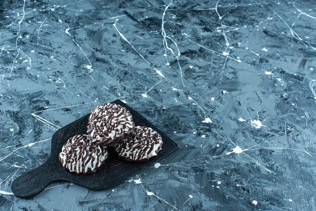 Biscotti al cioccolato su un tagliere, sul tavolo blu.