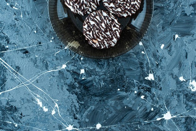 Biscotti al cioccolato su una lastra di vetro, sul tavolo blu.